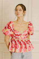 Woman wearing a pink floral top with a neutral background