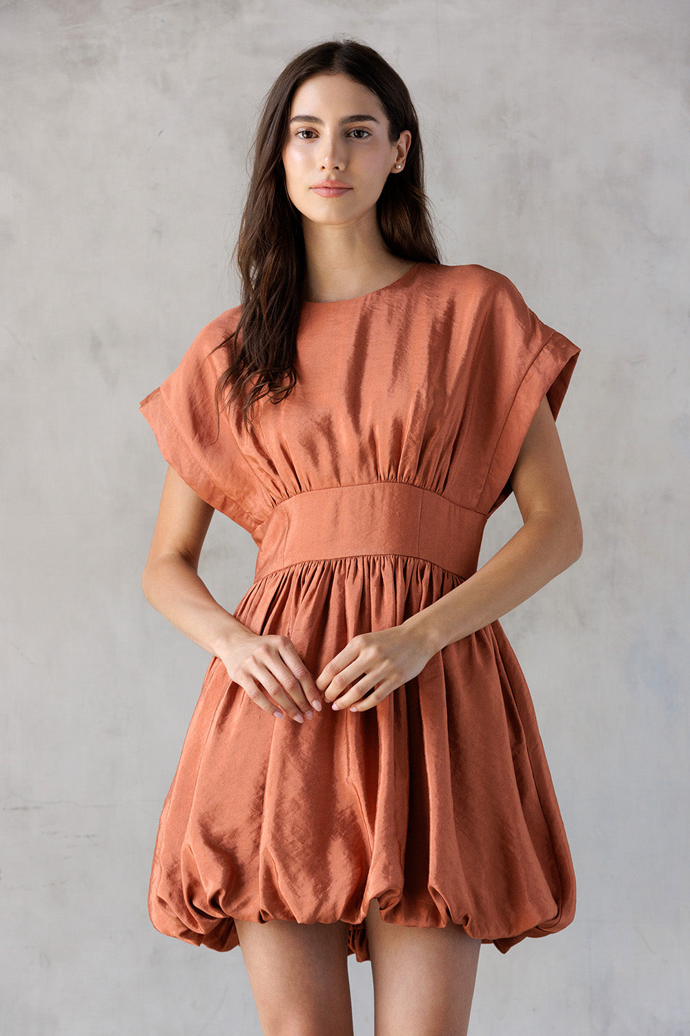 Woman wearing a rust-colored dress against a plain background