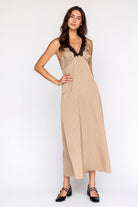 Woman wearing a beige polka dot dress with black lace details on a white background