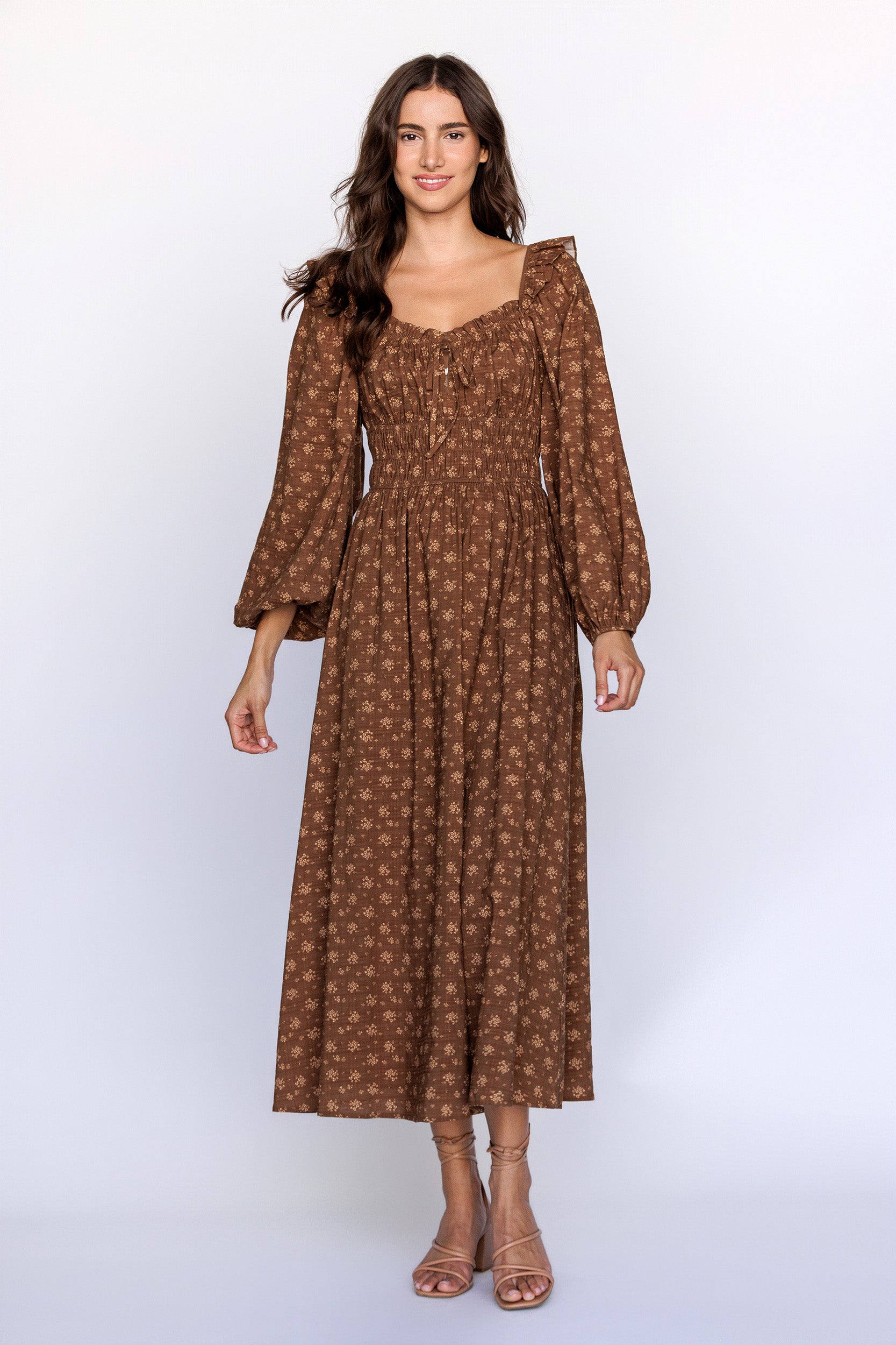Woman wearing a brown patterned dress with long sleeves on a white background