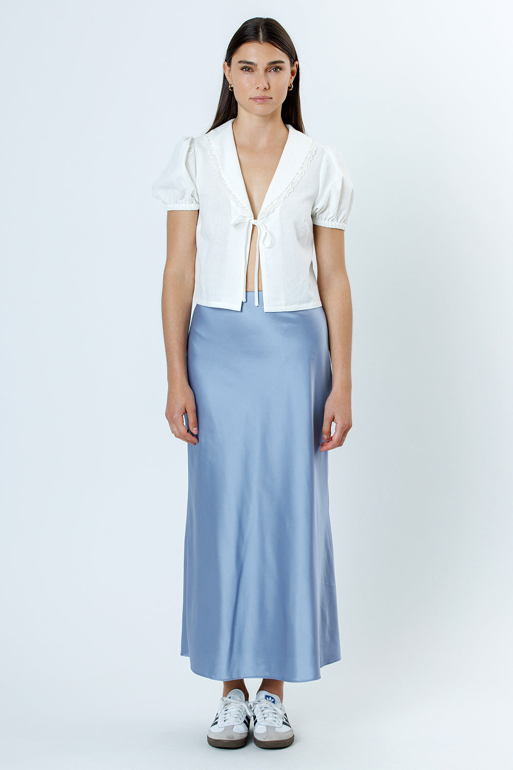 Woman wearing a white blouse and light blue skirt on a white background