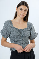 Woman wearing a black and white checkered blouse with puff sleeves on a white background