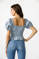 Back view of a woman wearing a blue checkered top and jeans on a white background 