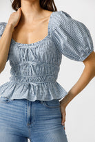 Woman wearing a blue checkered top and jeans on a white background