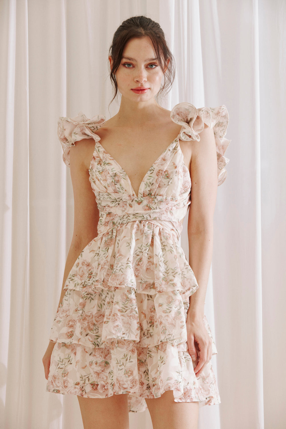 Blush floral ruffle mini dress with V-neckline, flutter sleeves, and tiered skirt