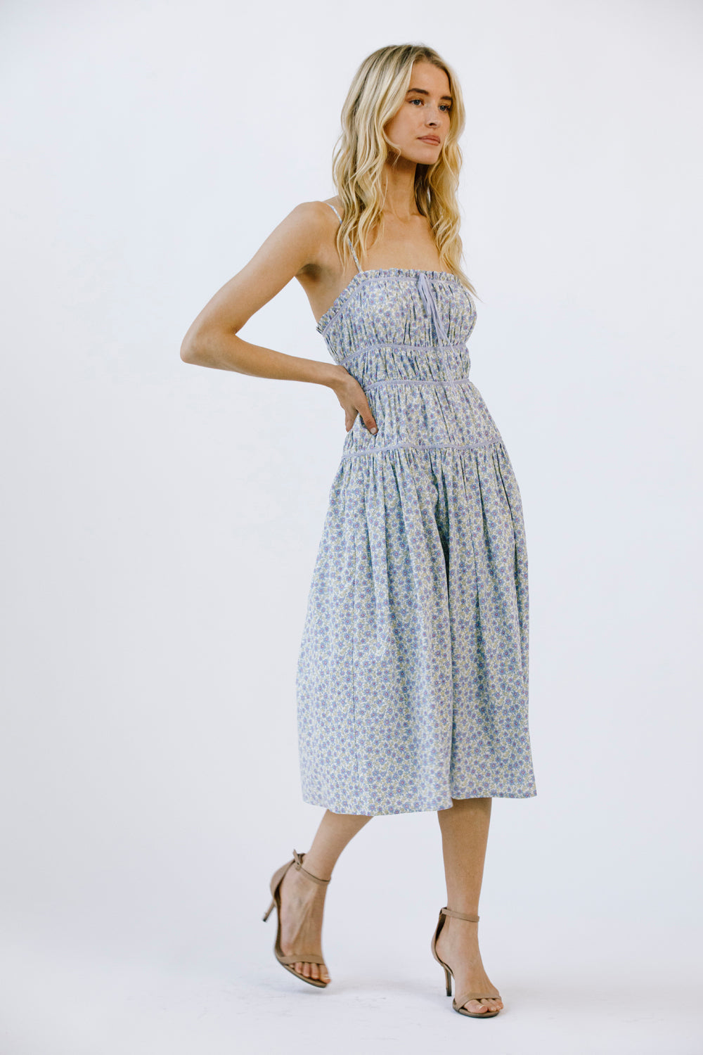 Side view of a woman wearing a blue floral midi dress on a white background