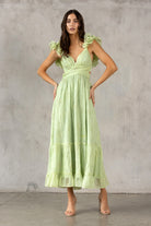 Woman wearing a lme green dress against a gray concrete wall