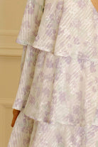 Lavender slip dress with floral and stripe pattern against a beige wall