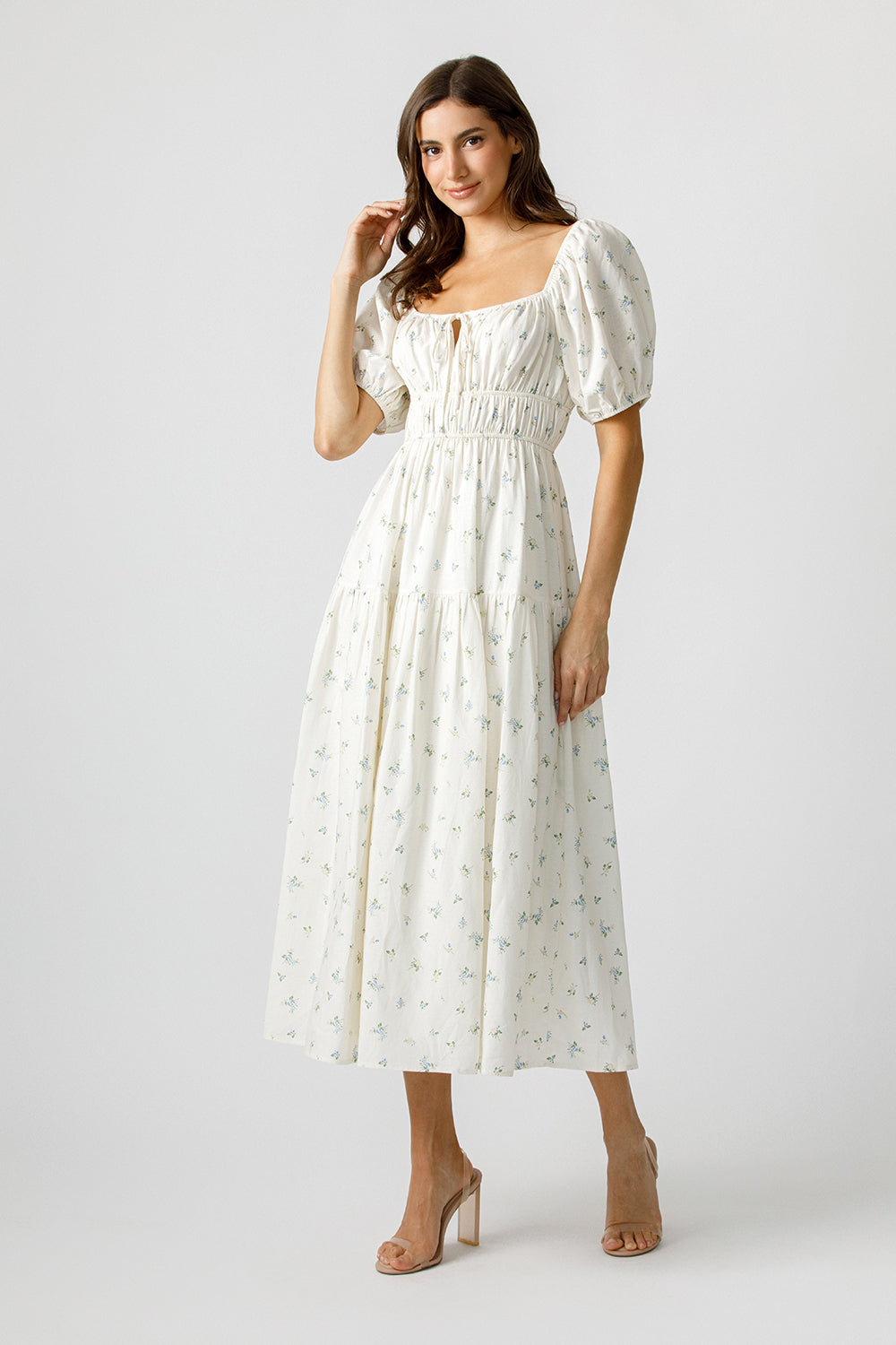 Woman wearing a cream floral dress on a plain background