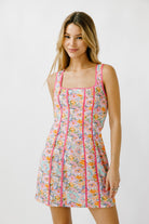 Woman wearing a floral dress with pink trim on a white background