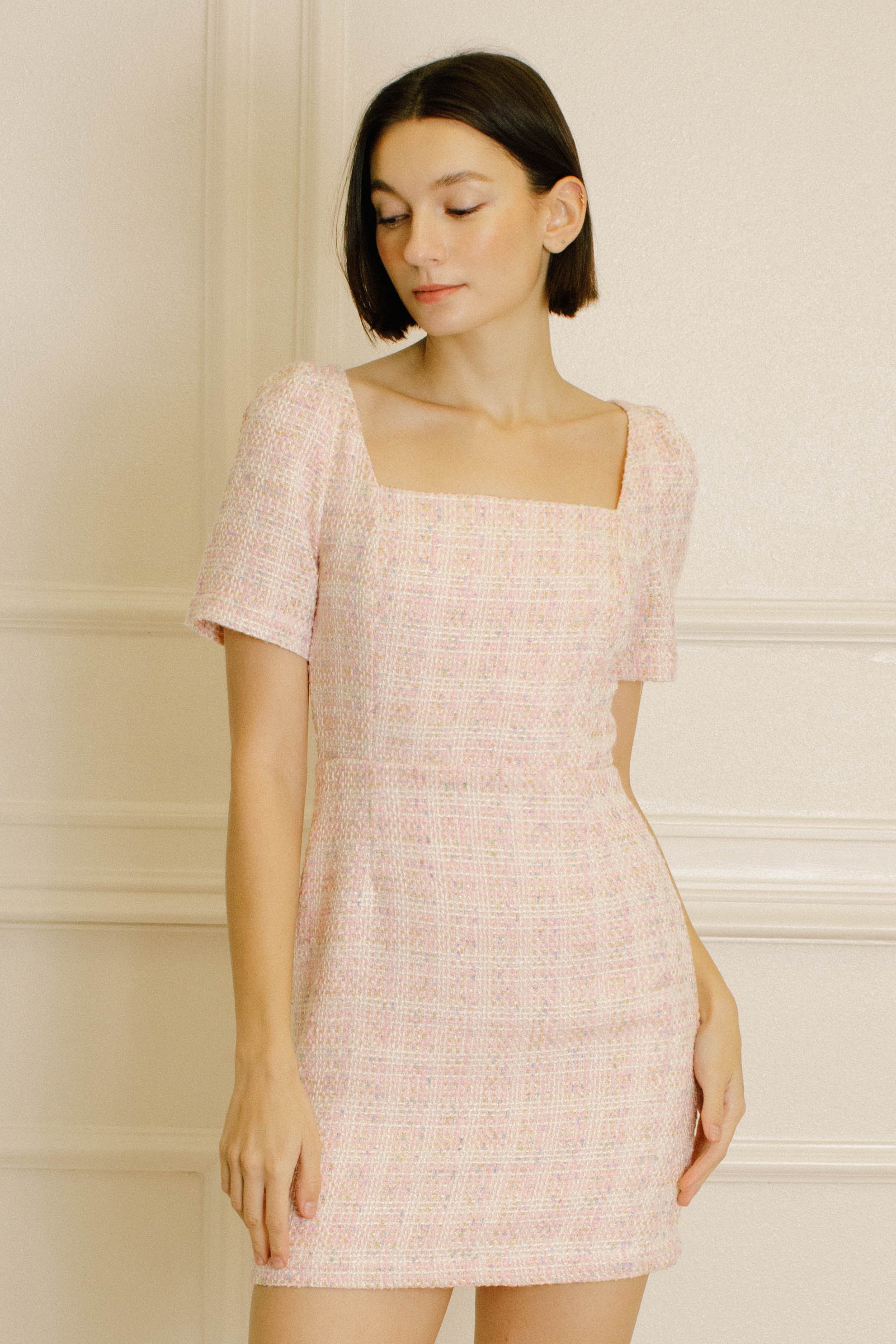 Woman wearing a pink patterned dress against a neutral background