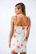 Back view of a woman wearing a white dress with thin straps on a white background 