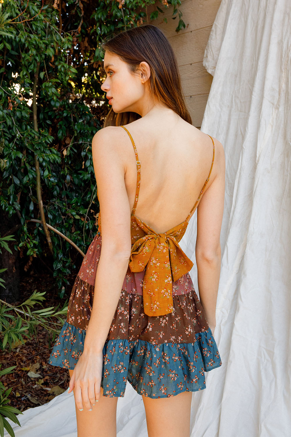 Woman wearing a floral dress with a tie detail in an outdoor setting