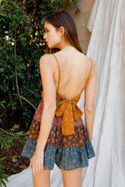 Woman wearing a floral dress with a tie detail in an outdoor setting