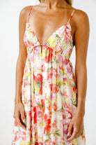 A dress with a vibrant red, yellow, and green floral print on a cream background