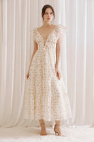 Woman wearing a floral dress against a white curtain background