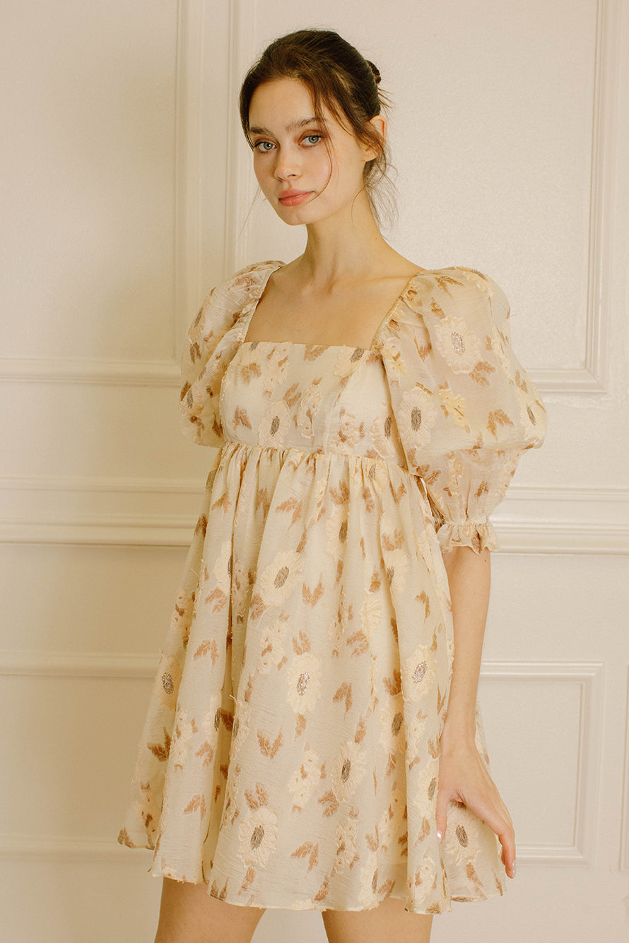 Woman wearing a beige dress with a floral pattern