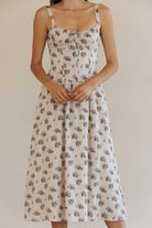 Woman wearing a beige floral dress against a plain background