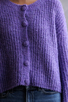 Close-up of a purple knitted cardigan with buttons.