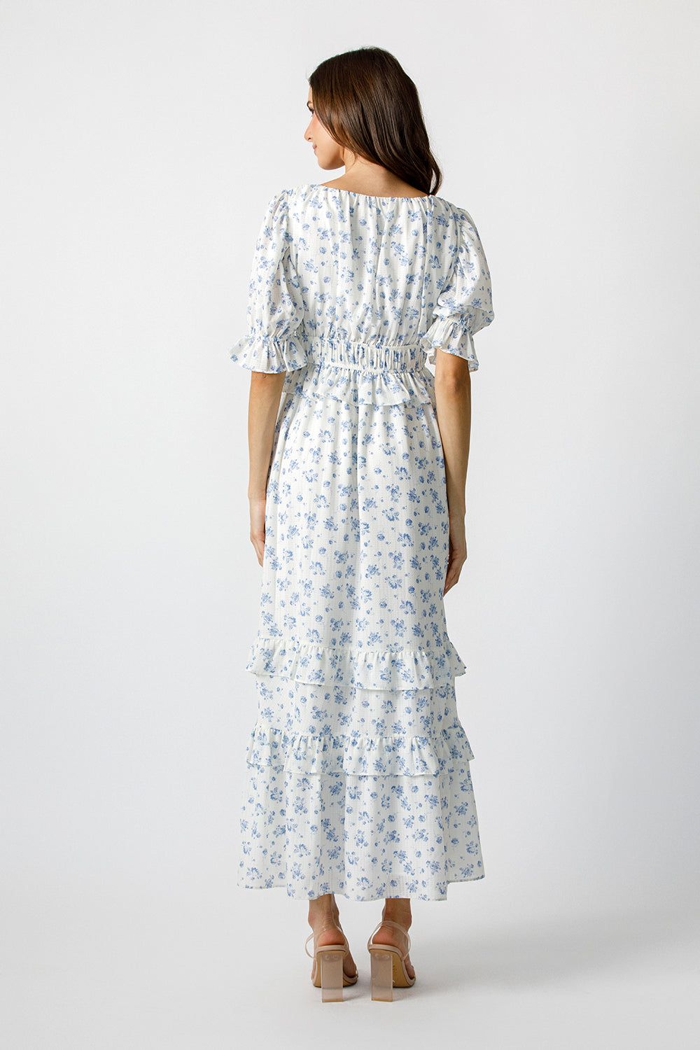 Woman wearing a blue floral pattern maxi dress on a white background