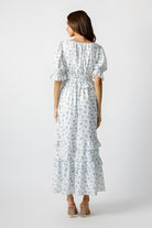 Woman wearing a blue floral pattern maxi dress on a white background