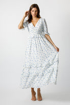 Woman wearing a blue and white floral dress and beige high-heels on a white background