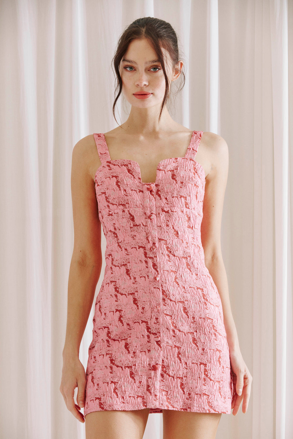 Woman wearing a pink and red bodycon dress against a plain background