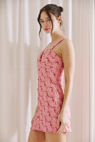 Side view of  woman wearing a pink and red bodycon dress against a plain background