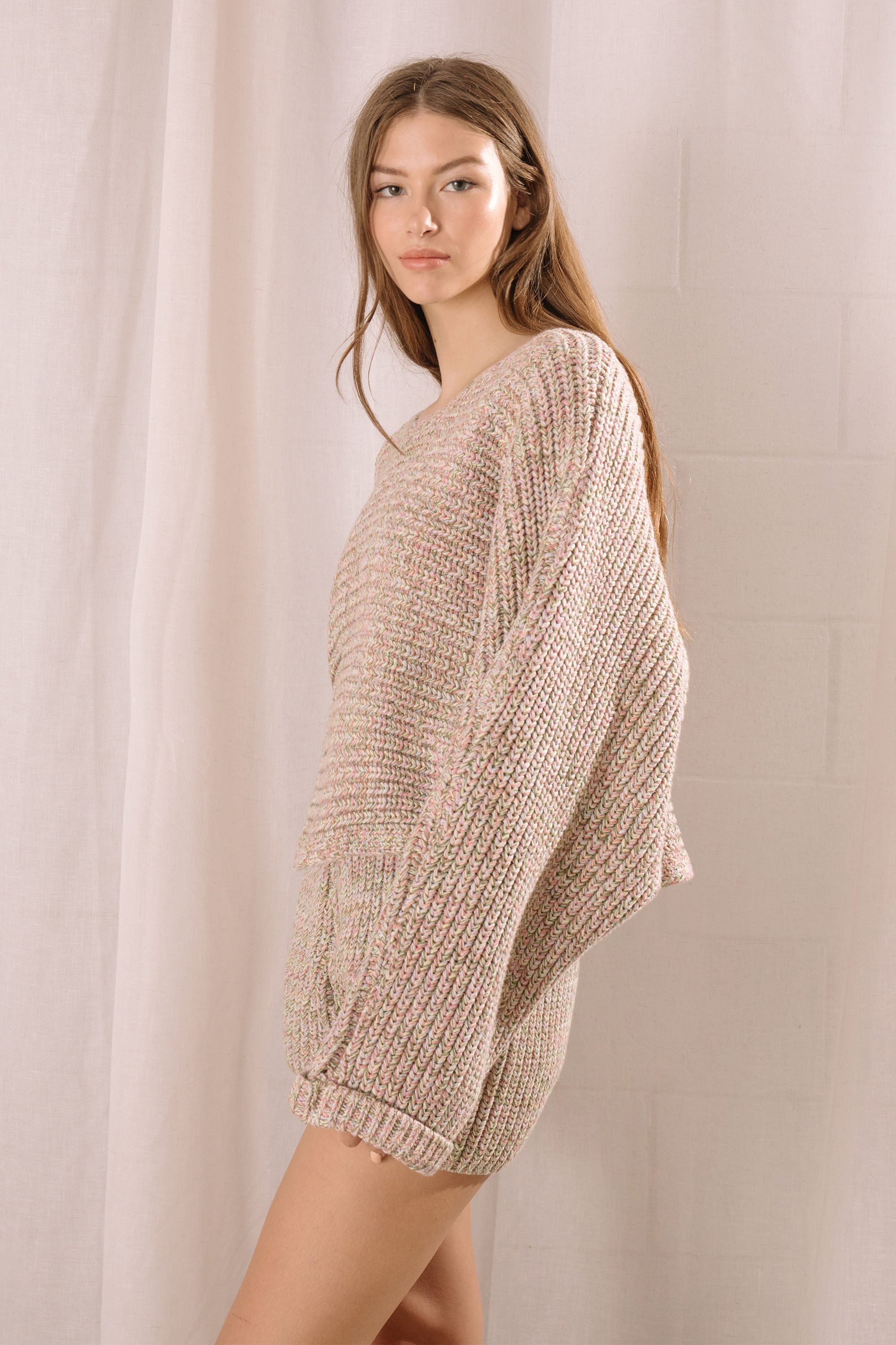 Side view of a woman wearing a knitted outfit against a plain background