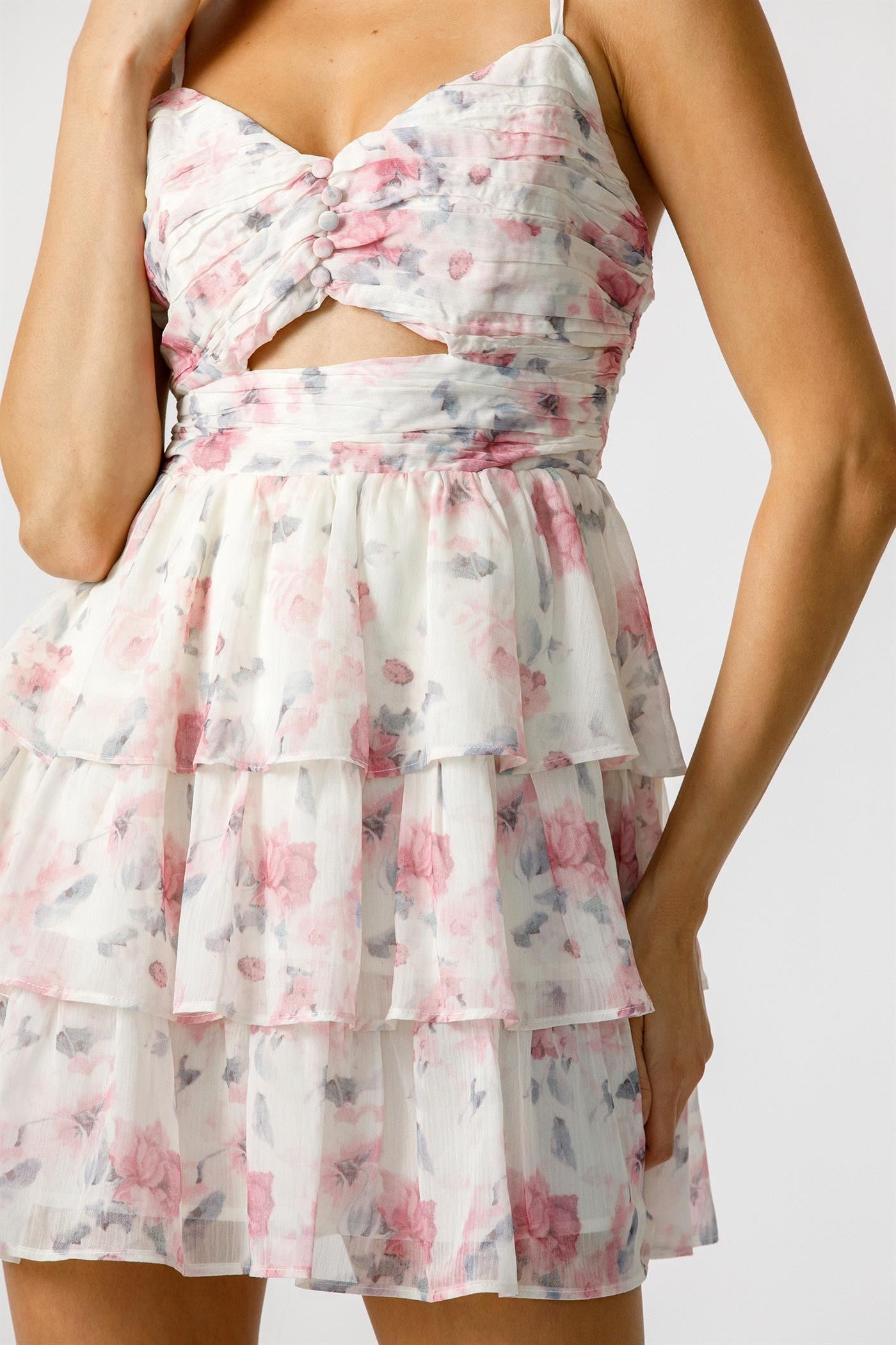 A woman wearing a floral chiffon mini dress with spaghetti straps and a front cutout.