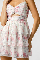 A woman wearing a floral chiffon mini dress with spaghetti straps and a front cutout.