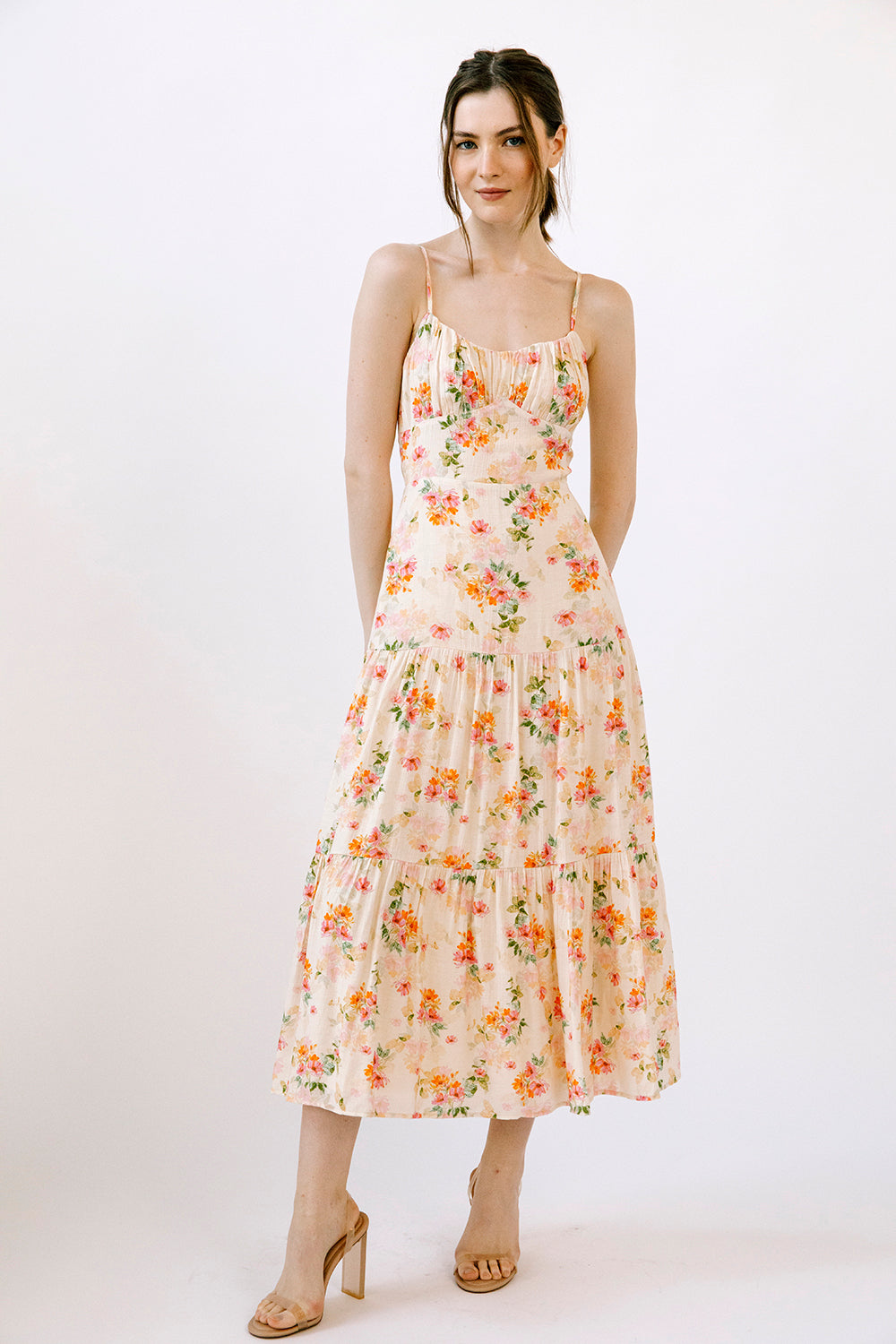 Woman wearing a cream dress with a watercolor-inspired floral pattern on a white background
