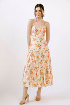 Woman wearing a cream dress with a watercolor-inspired floral pattern on a white background