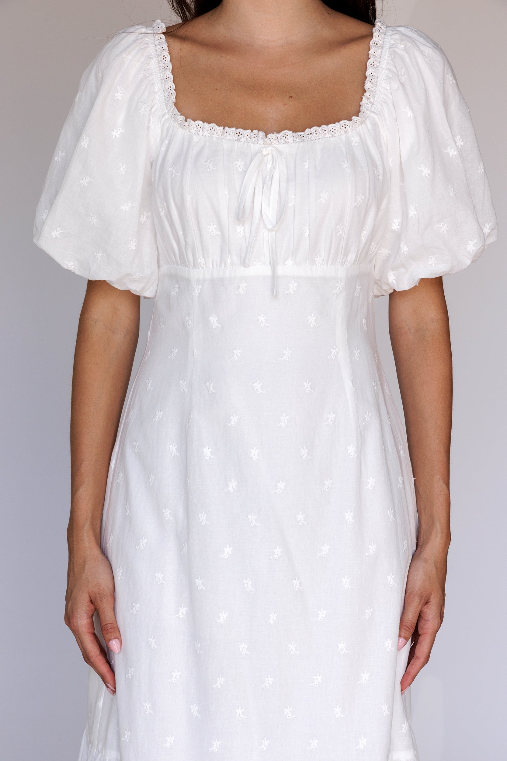 A white embroidered midi dress with puff sleeves and a square neckline.