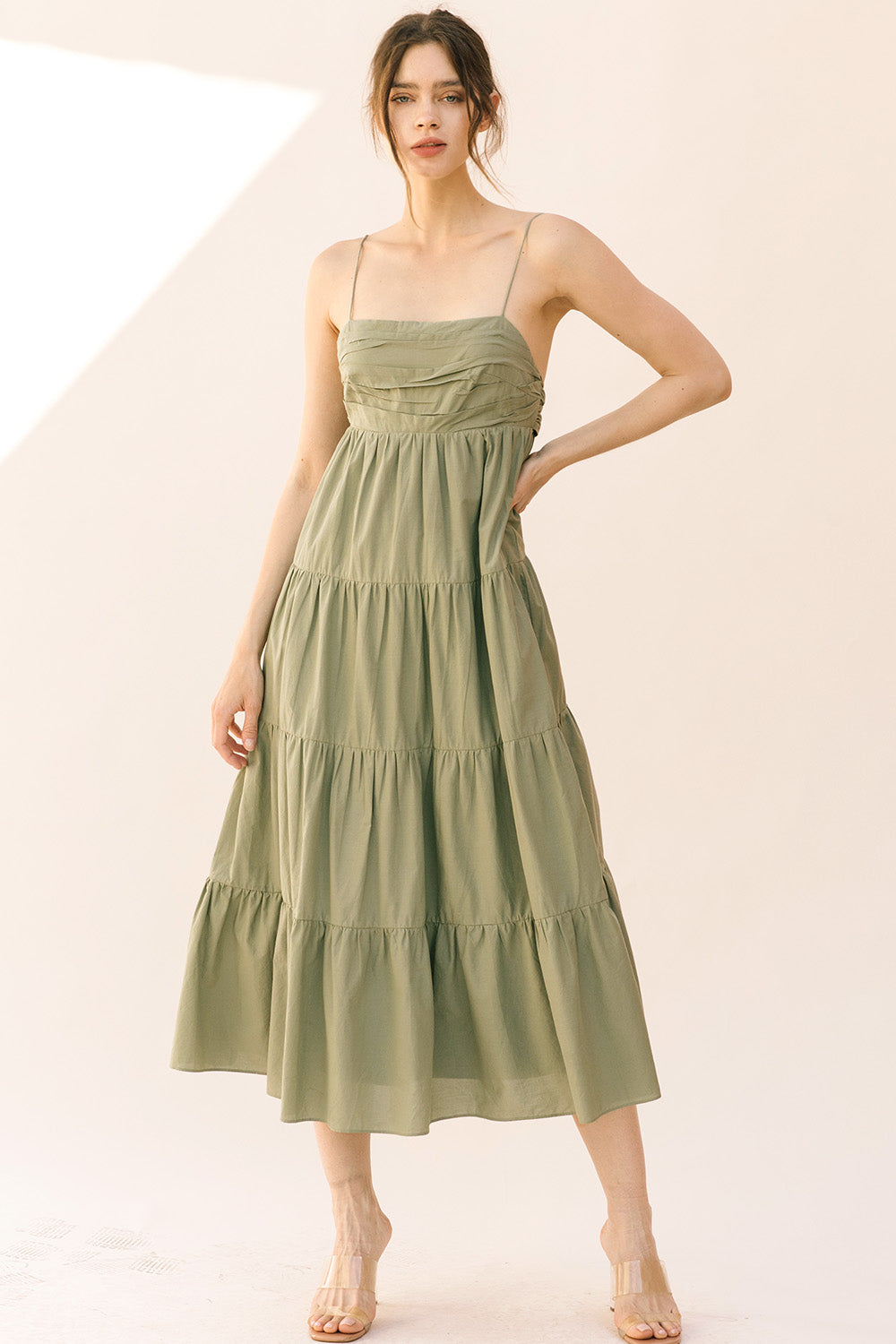 Woman wearing a green tiered dress on a plain background