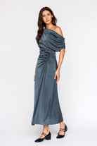 Woman wearing a teal one-shoulder dress on a white background