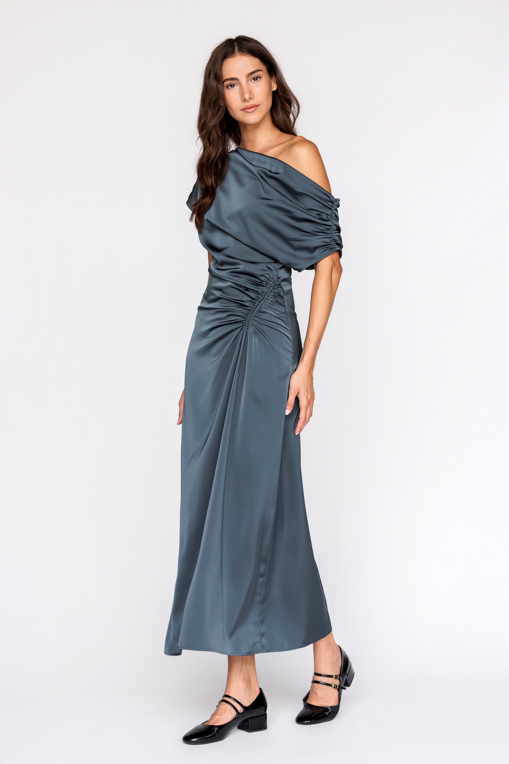 Woman wearing a teal one-shoulder dress on a white background