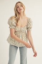 Model wearing a cream blouse with a floral pattern and denim jeans