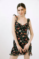 Woman wearing a black dress with a floral pattern against a white background