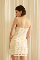 Back view of a woman wearing a cream bodycon dress against a plain background