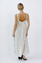 Back view of a woman wearing a polka dot dress on a white background