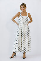Woman wearing a polka dot maxi dress on a white background
