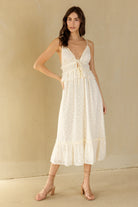 Woman wearing a cream midi dress against a beige background
