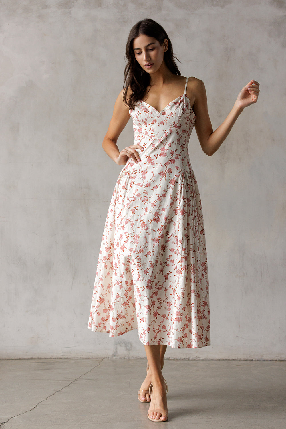Woman wearing a cream floral dress against a plain background