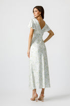 Back view of a woman wearing a soft pastel floral print maxi dress and fluttery short sleeves.