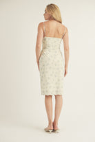 Back view of a woman wearing a floral slip dress on a plain background