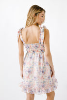 Back view of a woman wearing a floral dress on a white background