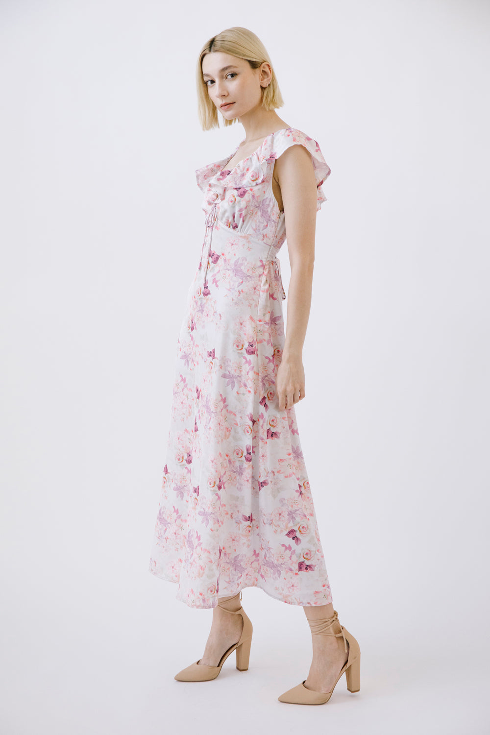 Woman wearing a floral dress and beige heels on a white background