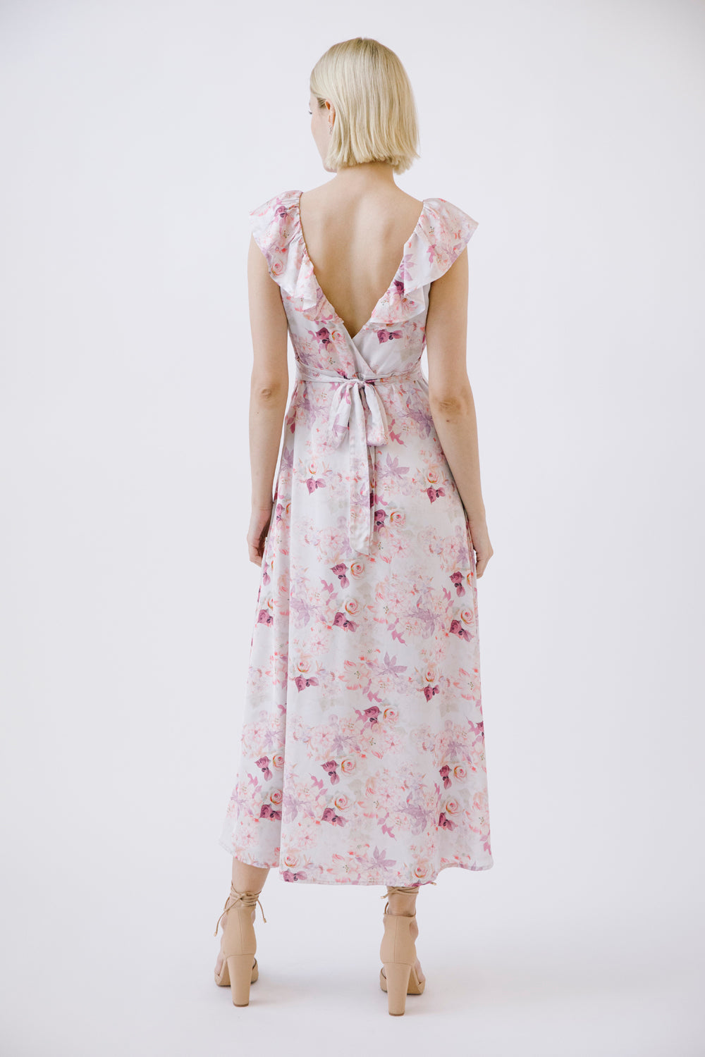 Woman wearing a floral dress with an open back on a white background