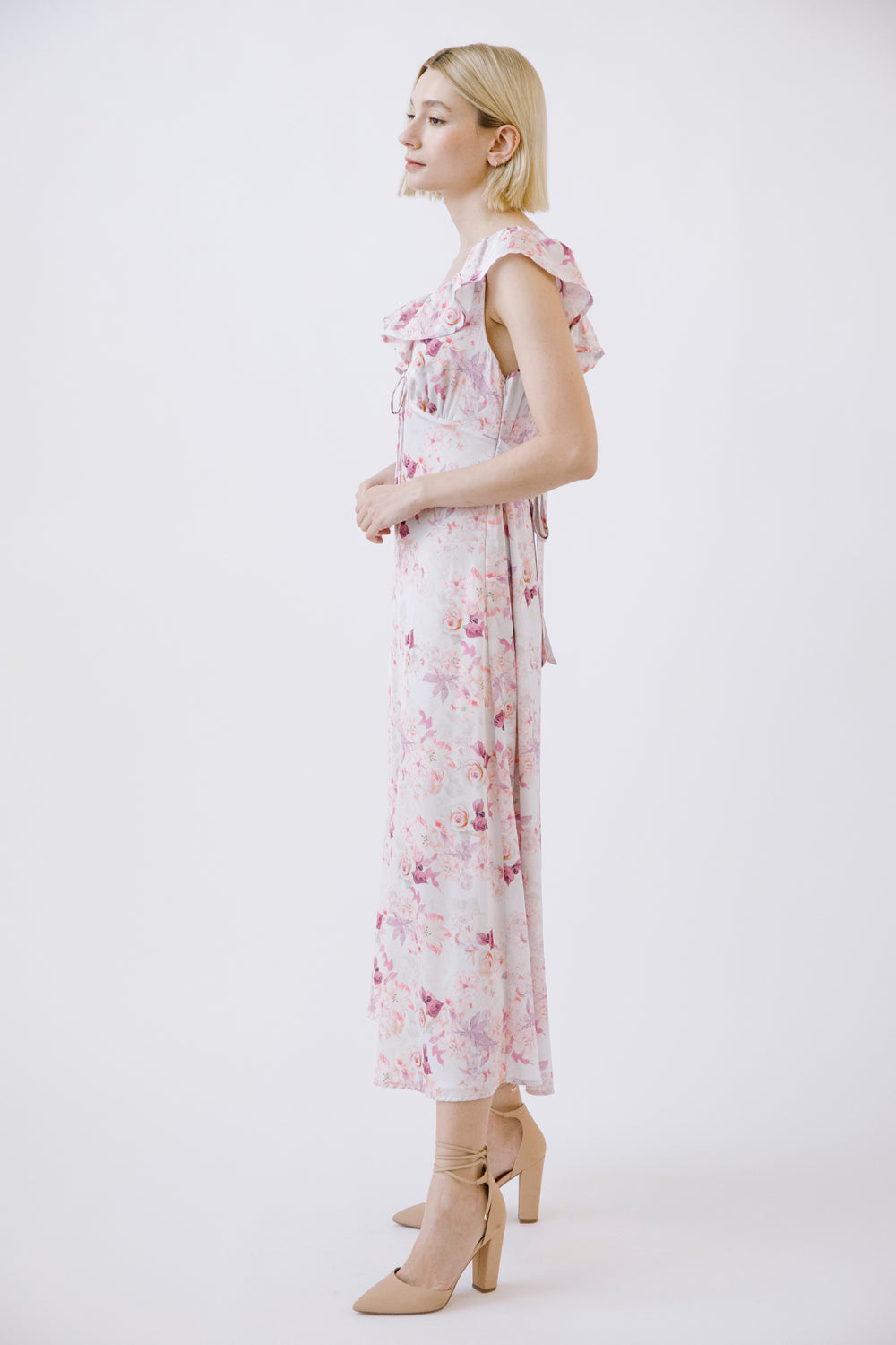 Side view of a woman wearing a purple floral dress on a white background